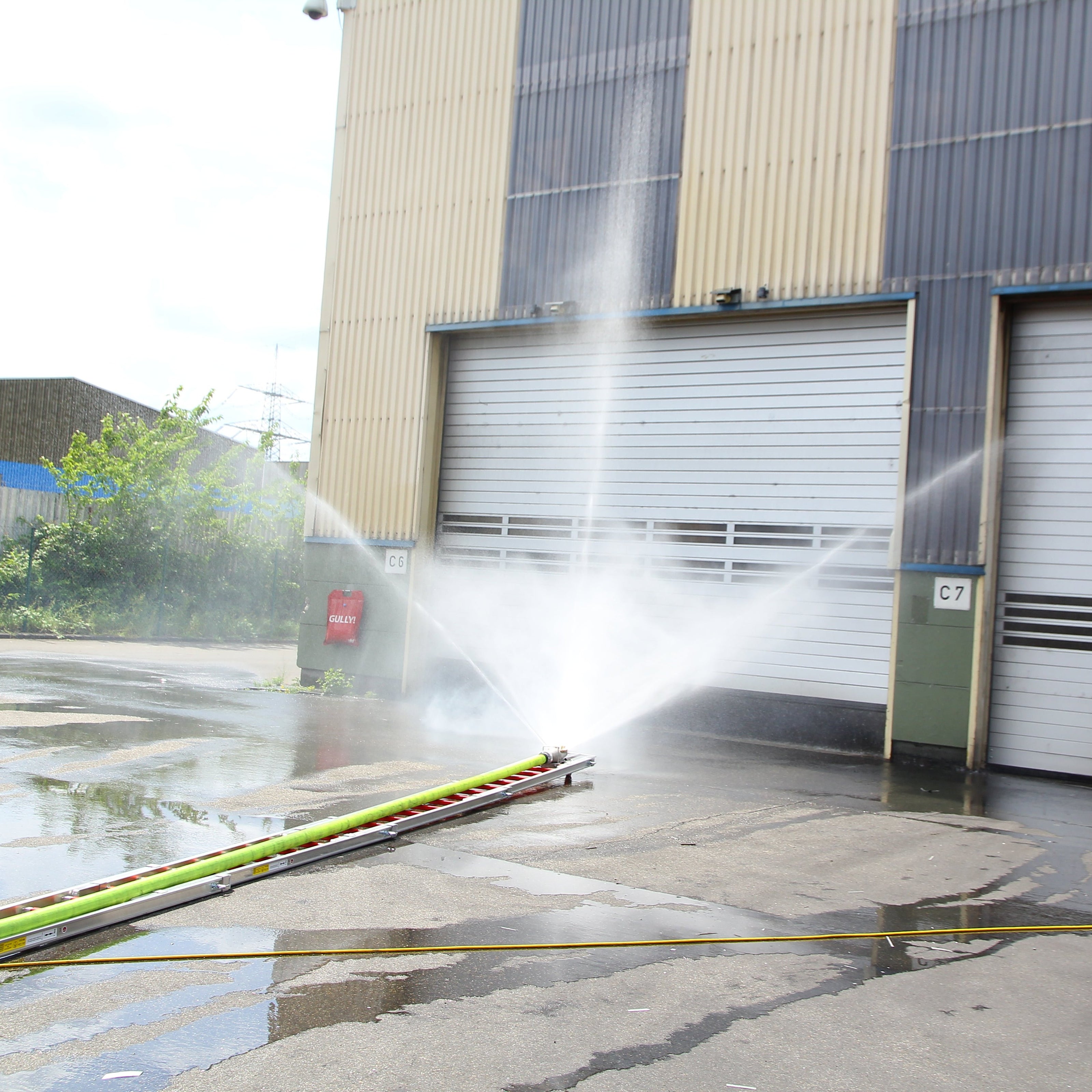 Innovative Feuerwehrtechnik wie der Löschigel auf einer Feuerwehr Steckleiter wie er von einer Werkfeuerwehr in eine brennende Industriehalle geschoben wird.